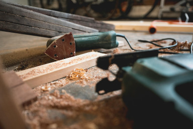 A saw sitting on wood, with sawdust around it.