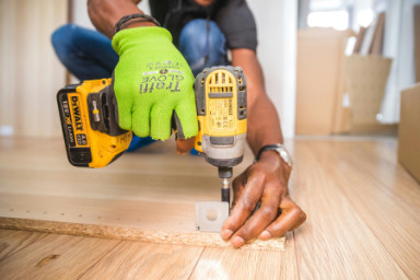 A man drilling a screw into a piece of wood.