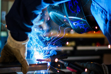 A pipe being welded with blue sparks flying.